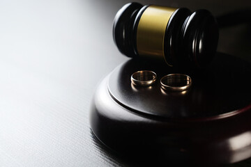 Wedding rings and judge gavel on dark table