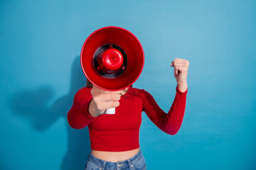 Young woman holding a red megaphone, wearing casual red top, blue jeans, vibrant background, promoting energy and confidence