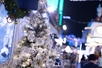 Several Christmas trees adorned with ornaments and lights brighten the evening atmosphere of a festive event shop inviting people to gather and celebrate