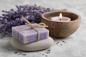 Organic bar of homemade soap tied with twine, Levander flowers around and lit candle. Natural environmentally friendly hygiene.
