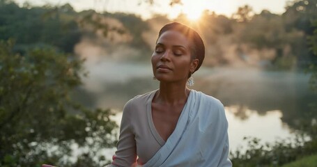 As sunrise brightening lakeside, breathing woman forming mudra on yoga mat at dawn, embracing light