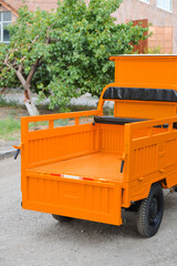 Orange electric cargo tuk tuk in the park