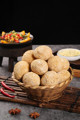 Fresh Whole Wheat Dinner Rolls in Wicker Basket with Vegetables and Spices on Dark Background
