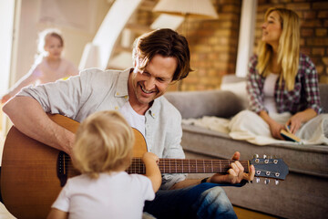 Young family playing together in the living room while the father is playing the guitar