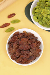 Xinjiang Green and Brown Raisins in White Bowls on Light Wood Background Two Color Origin Dried Fruit Display