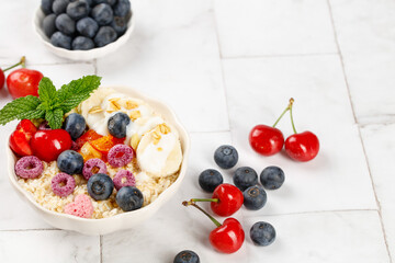 Healthy Oatmeal Bowl with Fresh Berries and Fruit on White Wooden Background - Light Breakfast for Weight Loss Diet