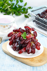 Fresh Red Seedless Grapes on White Plate with Mint Garnish and Vintage Tea Setting