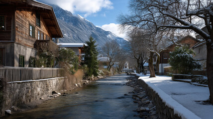 Obraz premium A serene winter landscape featuring a tranquil river, charming houses, and snow-capped mountains under a blue sky.