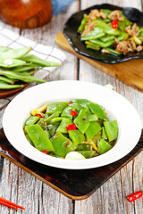 Stir-Fried Snow Peas with Red Peppers in White Bowl on Wooden Board - Healthy Asian Vegetable Dish