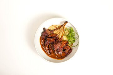 Top view of grilled lamb chops with sauce on plate