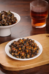 Spicy Stir-Fried Whelk Seafood Dish on Wooden Base with Tea