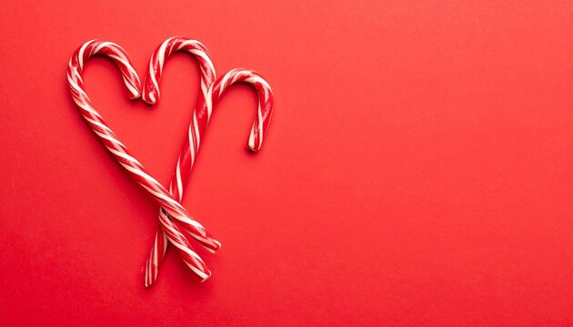 Three red-and-white candy canes on red background—two form a heart shape, one stands upright beside them—festive composition evokes holiday warmth, sweetness, and symbolic seasonal love. - Powered by Adobe