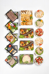 Top view of a full banquet set: fish, salads, appetizers, bread, and sushi on a white background