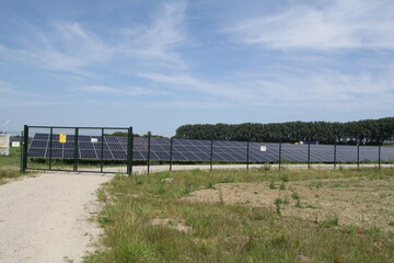 a large solar park with solar panels in the countryside and a blue sky