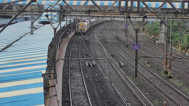 A Mumbai local train arriving at a platform, with multiple railway tracks on one side