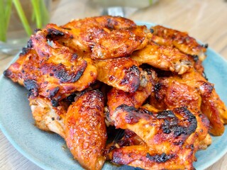 Delicious grilled chicken wings with a sweet and savory glaze served on a blue plate for lunch