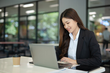  Asian businesswoman doing financial market research using laptop and digital tablet on digital investment in front of modern office.