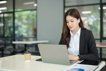 Asian businesswoman video chatting on laptop at office and modern building