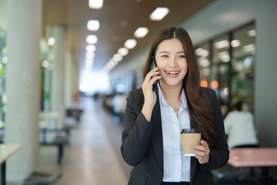 A businesswoman is walking in a modern building and talking on her mobile phone.