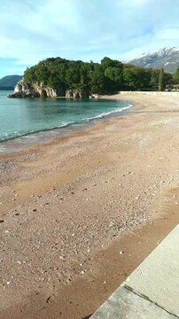 Romantic coastal escape in Budva Riviera: Milocer Beach with pink sand, pine park and snow-capped mountains. Adriatic Sea view: idyllic setting for couples and serene getaways in Montenegro.