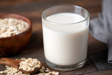 Dairy free gluten free oat milk in glass on wooden table, alternative lifestyle