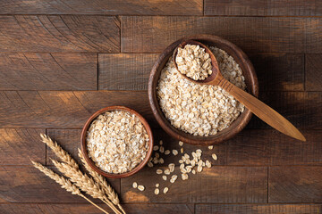 Rolled oats, oat flakes in a wooden bowl. Healthy cereals. Rustic style, top view