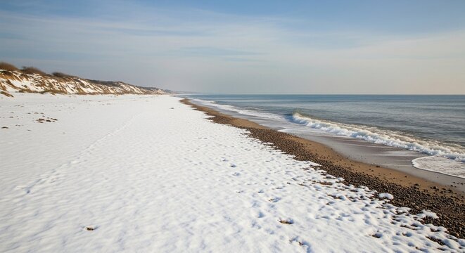 Spiaggia sovrastata dalla neve in un binomio estivo invernale