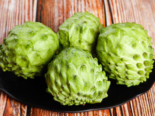 Fresh Noni Fruit on Black Plate - Tropical Superfruit with Bumpy Green Texture on Wooden Background