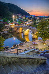 Evening view of Konjic showcasing the old bridge and town lights by the river
