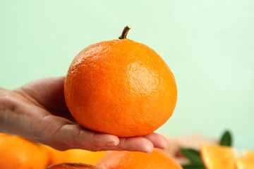 Fresh Orange Fruit in Hand Against Light Green Background - Healthy Citrus Concept