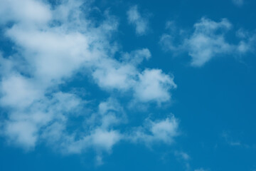 The sky is blue with clouds. The sun shines brightly, making the sky even brighter. The landscape is peaceful and serene.