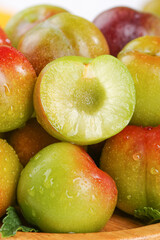 Fresh Colorful Plums with Water Droplets Showing Juicy Yellow Flesh in Cross Section Cut Display