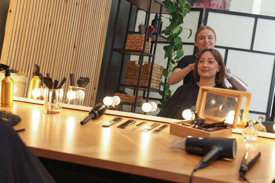 Hairstylist blow drying client's hair in salon
