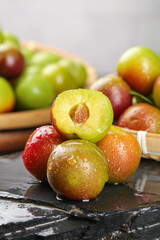 Fresh Ripe Plums Half Cut Display Showing Yellow Pulp and Pit on Slate Surface