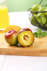 Fresh Cut Plums on Wooden Board with Orange Juice and Fruit Display in Modern Kitchen