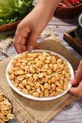 Roasted Peanut Kernels in Bowl with Hands on Rustic Wooden Table - Ready to Eat Healthy Snack