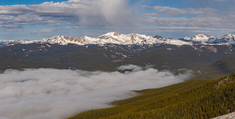 Spring panorama of a cloud inversion that remains in Taylor Park as a curtain of rain can be seen above still mostly snow covered Colorado 13er Italian Mountain. 