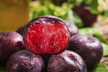 Fresh Purple Plums with Red Flesh Cut in Half on Wooden Table with Water Drops