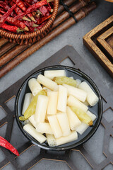Fresh lotus root slices and sour mixed vegetables with hot red chilli peppers in traditional Asian cooking setup