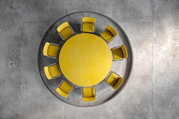 A sunlit yellow conference table surrounded by modern chairs in a meeting room