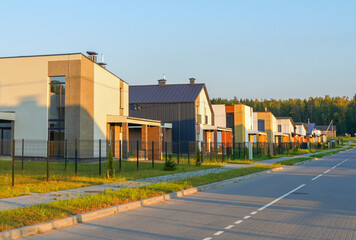 Fototapeta premium Suburb houses Rows along road. Prefab house. Street in private residential area. Contemporary Residence in suburb. Family house, Modern Home outside city. Modern Barn house Villa in suburban area.