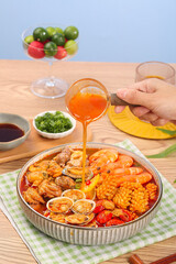 Spicy Seafood Hot Pot with Fresh Shrimp and Clams Being Served with Sauce Ladle on Wooden Table