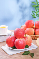Fresh Red Apples on White Plate with Tea Cup and Wicker Basket on Wooden Table