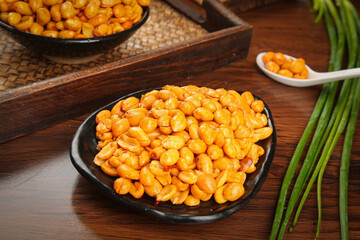 Spicy seasoned peanuts in black bowls - roasted nuts snack food on wooden table