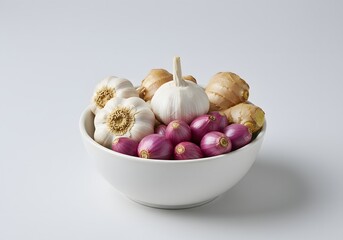 A white bowl filled with fresh garlic bulbs, ginger roots, and small red shallots, presented on a clean white background.