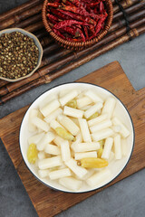 Pickled lotus root vegetables with spicy chili and coriander seeds on bamboo tray