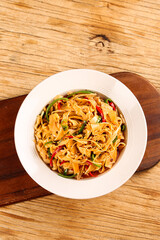 Spicy Asian Noodles with Bamboo Shoots and Shredded Vegetables on Wooden Table