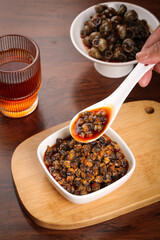 Spicy Stir-Fried Whelk Seafood Dish on Wood Base with Traditional Ceramic Spoon