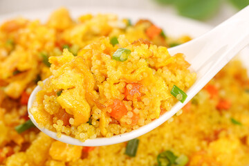 Golden turmeric rice with vegetables on spoon - healthy grain dish with shallow depth of field