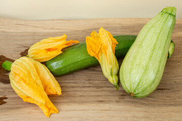 Courgettes and zucchini with yellow flowers on wooden desk, choice concept, copy space backdrop
